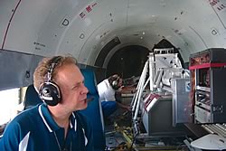 Photo showing A NOAA scientist aboard a DC-3 aircraft studying a real-time display of ozone and aerosol data for the New England Air Quality Study.
